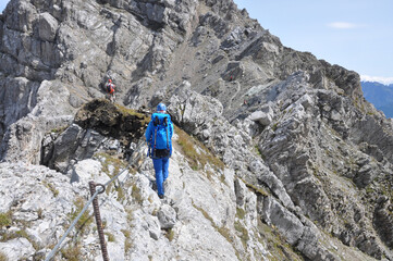 Kobieta ubrana na niebiesko asekuruje się lonżą na via ferracie, Dolomity