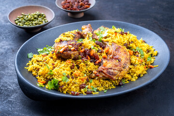 Modern style traditional fried Arabic chicken majboos with chicken leg and jeweled rice served as close-up in a design plate