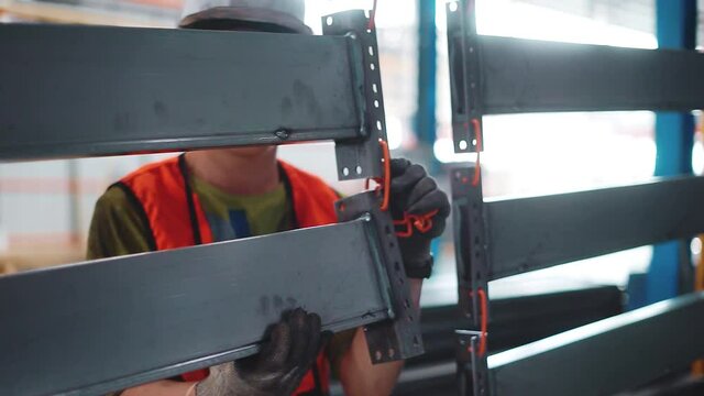A uniformed worker hangs metal panels on an overhead conveyor for painting.