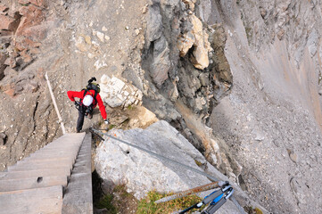 Fototapeta premium Człowiek w białym kasku stoi pod drabiną na via ferracie, Dolomity, Włochy