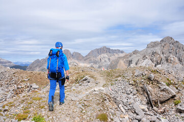 Kobieta ubrana na niebiesko idzie szlakiem w Dolomitach