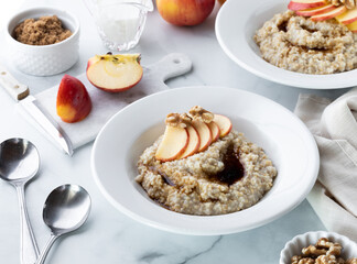 Breakfast bowls of steel cut oats with brown sugar and apple slices ready for eating.