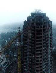 large abandoned unfinished brick building skyscraper and big yellow machine crane