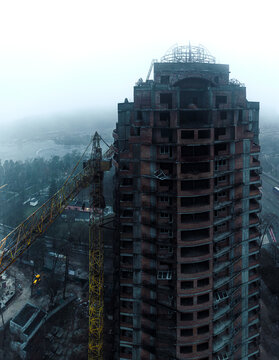 large abandoned unfinished brick building skyscraper and big yellow machine crane