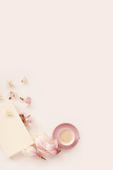 beautiful tender flat still life, card on a beige background, magnolia buds, a cup of cappuccino, concept of a floral spring background