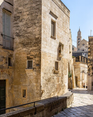 Fototapeta na wymiar Scenic street in Sassi of Matera historic district leading with Matera Cathedral in the background, Italy
