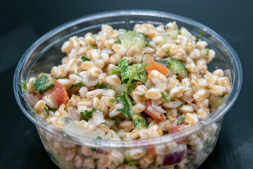 Farro grain served by the pound in clear plastic container for presentation of the savory contents.