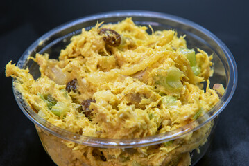 Curried Chicken Salad served by the pound in clear plastic container for presentation of the savory contents.