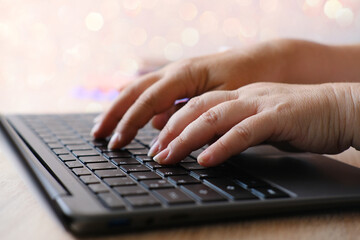 woman is typing on laptop keyboard, selective focus, working in evening at laptop of his house, hands closeup, concept of remote work, quarantine, downshifting