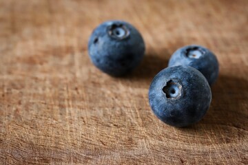 A close up shot of some fresh juicy blueberries on a wooden cutting board.