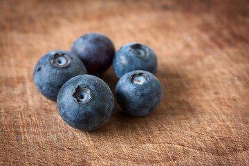 A close up shot of some fresh juicy blueberries on a wooden cutting board.