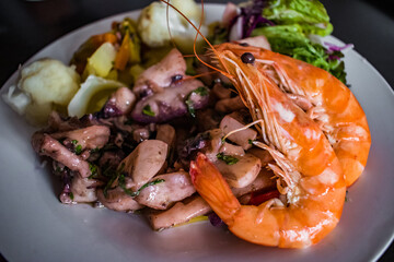 Dish with shrimp and composed with cuttlefish stew and vegetables with selective focus