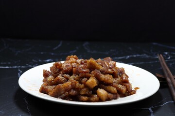 Fried and stirred cutting belly pork with traditional sauce and pepper serving on the plate. Famous side dish menu in Asian restaurant. 