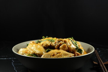 Steamed chicken with red curry and basil serving in the bowl. Famous traditional spicy chicken in Thai style. 