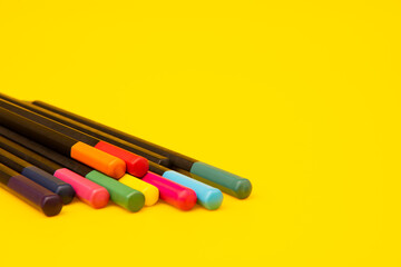 Colored pencils on yellow background with copy space