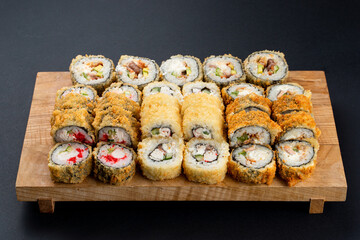 All types of fried sushi rolls from a sushi restaurant on one board, top view, studio menu photography