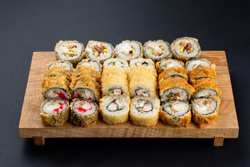 All types of fried sushi rolls from a sushi restaurant on one board, top view, studio menu photography