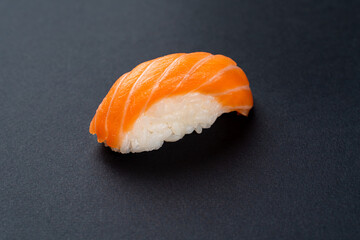 Single salmon sashimi on black background, close up, texture is visible