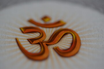 Close up image of the OM symbol in orange color with white background, shot in landscape composition