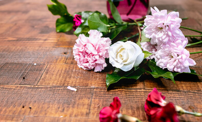 Closeup front view of blossom flowers with fresh green leaves lay on a wooden table surface. Arranging white rose and pink florals for decoration on a special day. Happy romantic love concept.