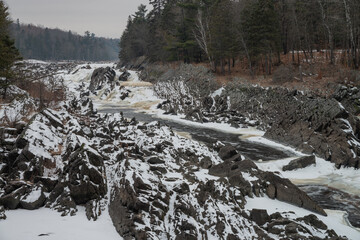 River valley with frozen river, sharp black rocks