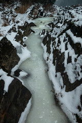 Close view of a frozen creek with sharp black rocks