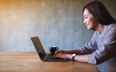 Closeup image of a beautiful asian woman working and typing on laptop computer keyboard on the table