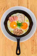 Fried eggs in a black pan placed on a wooden table