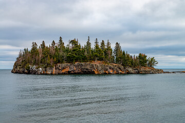 Island with coniferous trees and orange moss near lake Superior