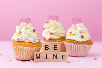 Valentine's day card. Be mine. Cupcakes decorated hearts on a pink background