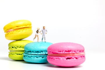 Miniature people , couple running on colourful french macaroon , Valentines day concept
