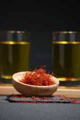 Crocus flower with wooden bowl and saffron flower essence isolated on dark background.