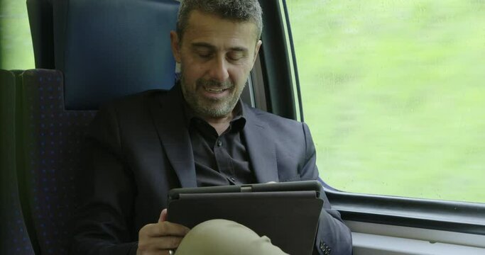 Man with tablet on a train commuting smiling