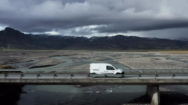 Car travels on scenic road in Iceland crossing bridge over glacial melt water