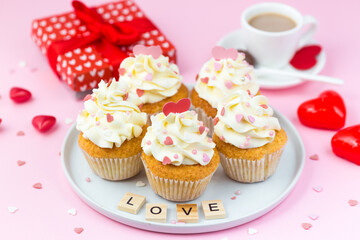Valentine's day sweets. Cupcakes decorated hearts, gift box and cup of coffee on a pink background