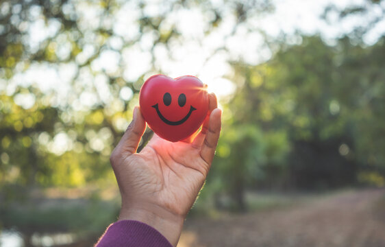 Woman Hand Holding Red Heart And Smile Face.