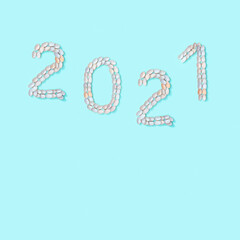 Figure 2021 laid out of small similar natural seashells on blue paper. Summer design concept with shells