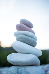 White pebble stones pyramid on beach symbolizing stability, zen, harmony, balance with forest background