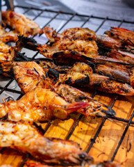 camarones asados , asándose montados en reja de asados y presentados por las manos del chef 