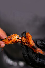 camarones asados a la parrilla  presentados por chef con guantes negros 