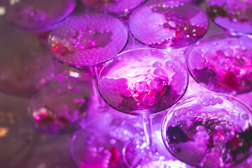 Glasses with alcoholic beverages in the pyramid, filling and pouring beautiful pyramid line of different colored alcohol cocktails with champagne on a party, catering banquet table