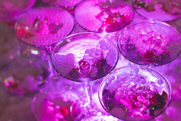 Glasses with alcoholic beverages in the pyramid, filling and pouring beautiful pyramid line of different colored alcohol cocktails with champagne on a party, catering banquet table