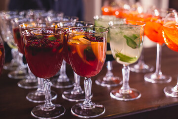 View of alcohol setting on catering banquet table, row line of different colored alcohol cocktails on a party, martini, vodka, spritz and others on decorated catering table event