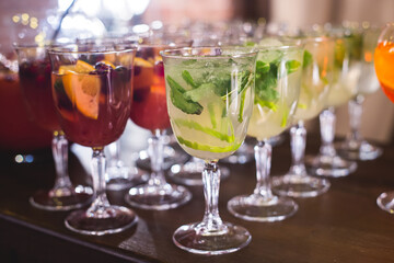 View of alcohol setting on catering banquet table, row line of different colored alcohol cocktails on a party, martini, vodka, spritz and others on decorated catering table event