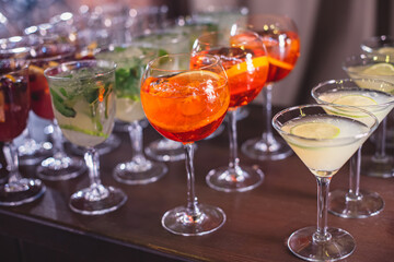 View of alcohol setting on catering banquet table, row line of different colored alcohol cocktails on a party, martini, vodka, spritz and others on decorated catering table event