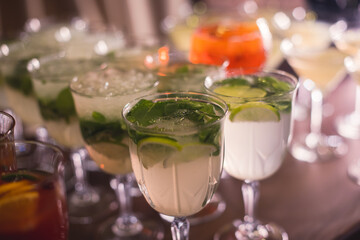View of alcohol setting on catering banquet table, row line of different colored alcohol cocktails on a party, martini, vodka, spritz and others on decorated catering table event