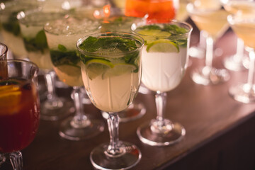 View of alcohol setting on catering banquet table, row line of different colored alcohol cocktails on a party, martini, vodka, spritz and others on decorated catering table event