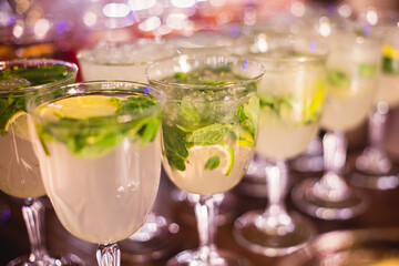 View of alcohol setting on catering banquet table, row line of different colored alcohol cocktails on a party, martini, vodka, spritz and others on decorated catering table event