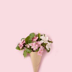 Flat-lay of paper craft cone with white pink apple blossom flowers over pastel light pink background, top view. Spring or summer mood concept, 8 march woman day, Happy Easter card, copy space