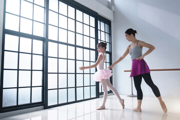 Fototapeta na wymiar Little ballerina dancing with ballet teacher in dance studio